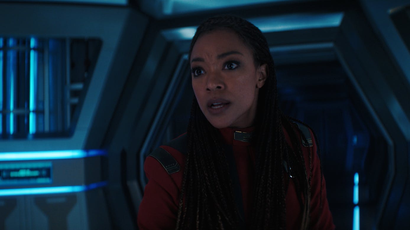 Captain Burnham stands in shock in a corridor aboard the Discovery and she looks straight ahead in 'Face the Strange'