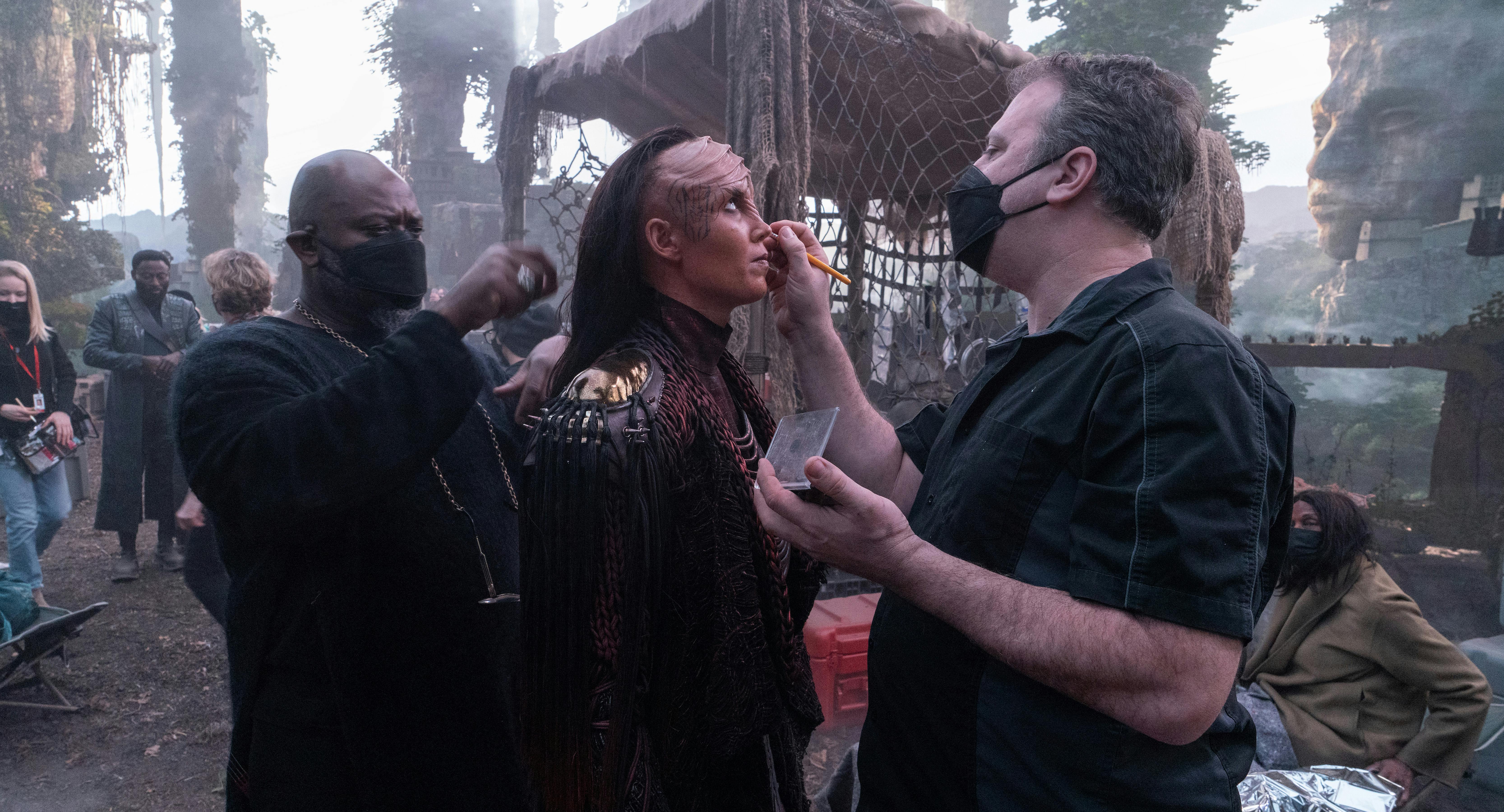 Behind-the-scenes still of hair and make-up touching into a background actress portraying a Klingon in Star Trek: Strange New Worlds