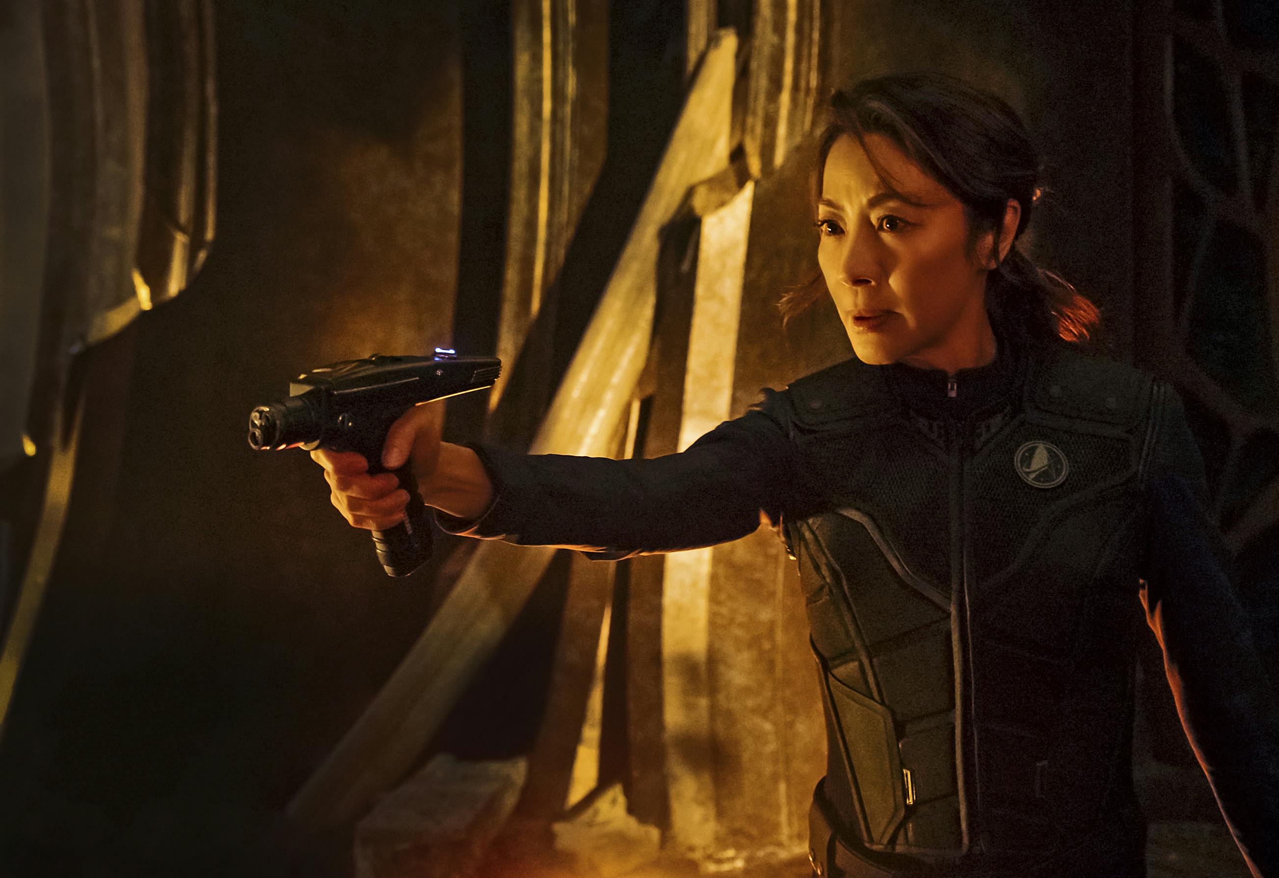 On the Klingon ship, Captain Georgiou, in tactical uniform, holds her phaser in front of her as she navigates enemy territory in 'Battle at the Binary Stars'